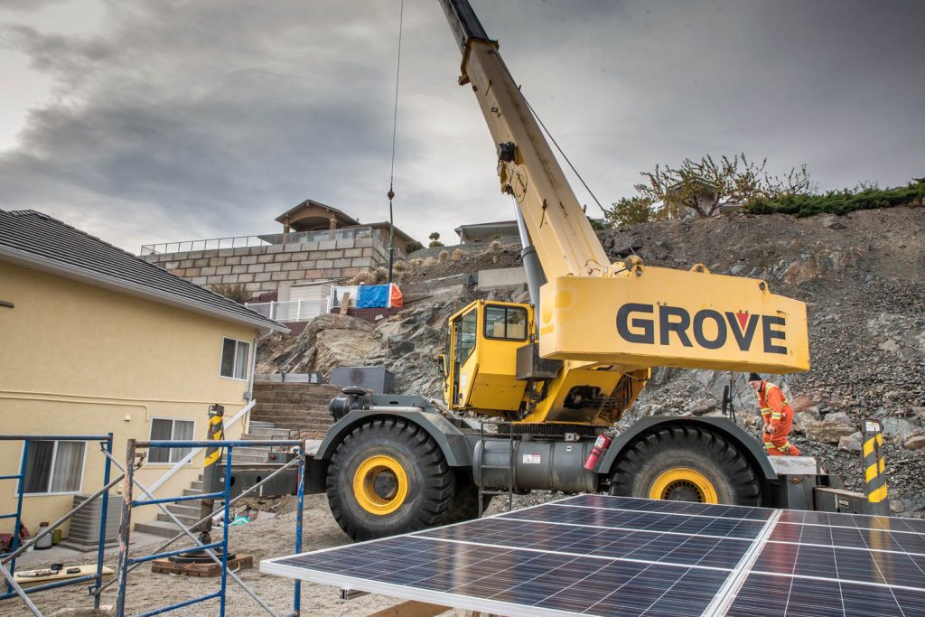 A crane is prepared to lift a wall of solar panels to a pole on the hill behind Paul McCavour's house. There McCavour will be able to angle them according to the season to capture the most sunlight. McCavour preaches the merits of solar power to reduce electricity bills over the longer term and contribute to a greener planet. (Richard McGuire photo)
