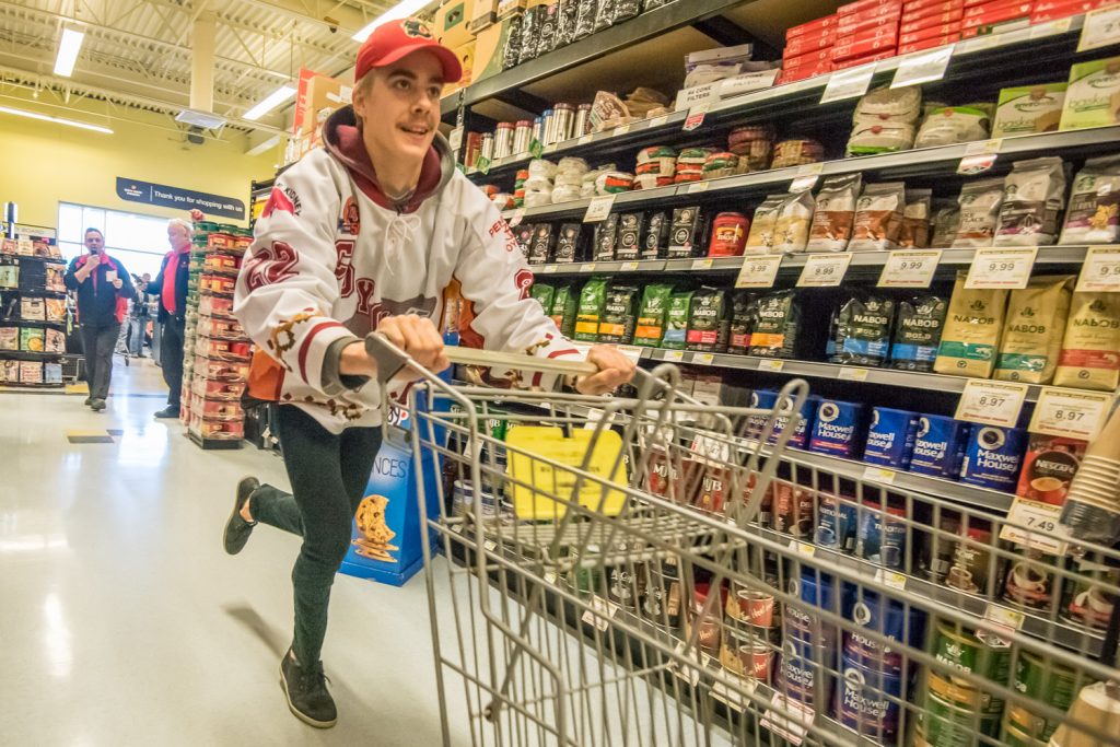 Osoyoos Coyotes Captain Daniel Stone makes a beeline for the meats, racing down the coffee aisle, as he does the legwork for Joanne Patterson, who won a one-minute shopping spree at Buy-Low Foods Thursday. (Richard McGuire photo)