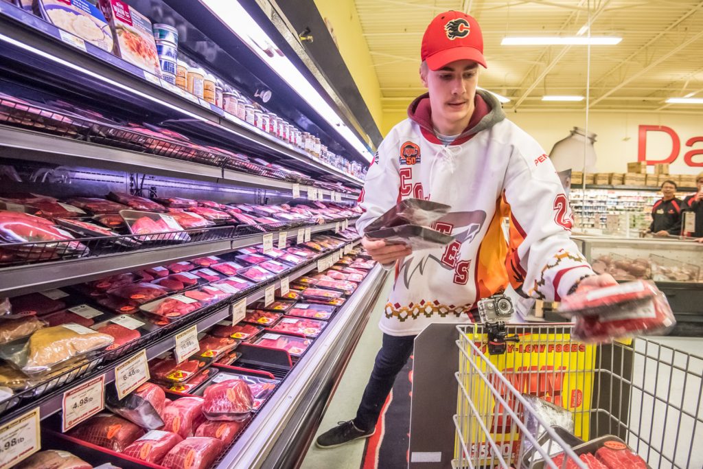 Osoyoos Coyotes Captain Daniel Stone quickly loads his shopping cart with meat as he does the legwork for Joanne Patterson, who won a one-minute shopping spree at Buy-Low Foods Thursday. Patterson instructed Stone on what she wanted him to grab -- the most expensive meats -- and she was pleased with the job he did. (Richard McGuire photo)