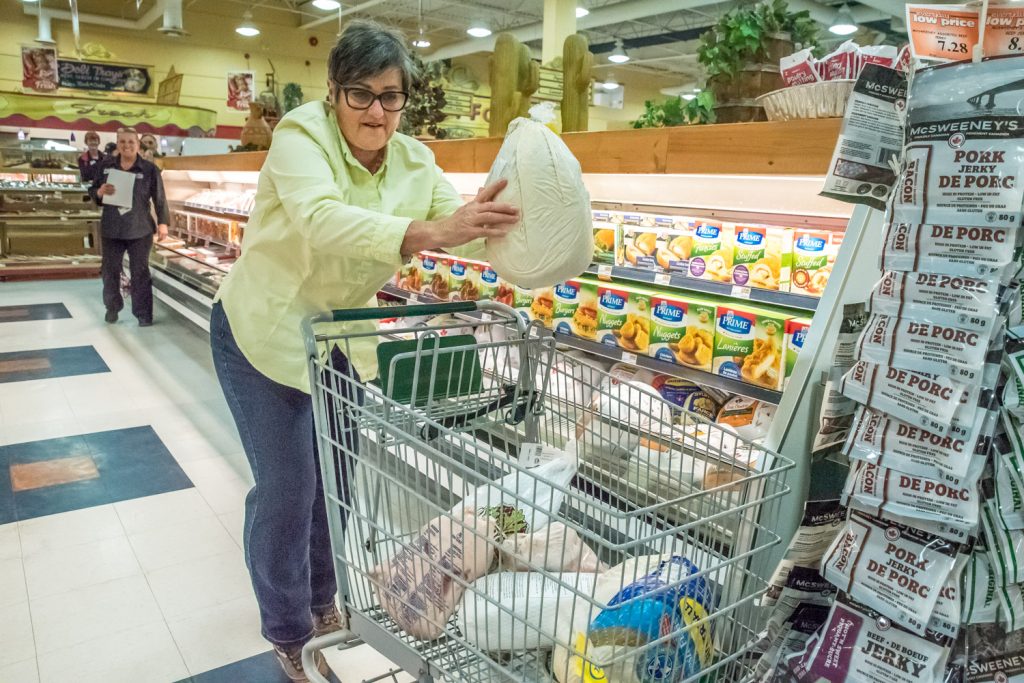 Wendy Mellace shoves a frozen turkey into her shopping cart during a 30-second shopping spree at AG Foods. She had her route planned ahead of time and managed to grab all she was after -- $387 worth of groceries. (Richard McGuire photo)