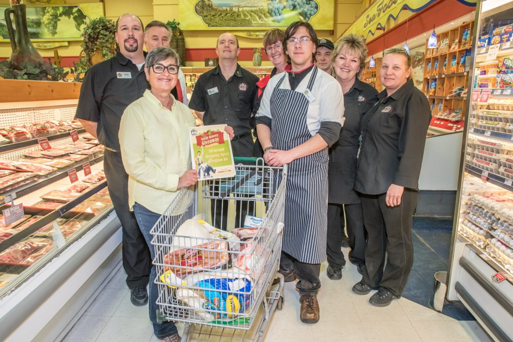 Wendy Mellace shows her shopping cart stuffed with meat products after winning a 30-second shopping spree at AG Foods. Posing with her are store employees, who watched the excitement. (Richard McGuire photo)