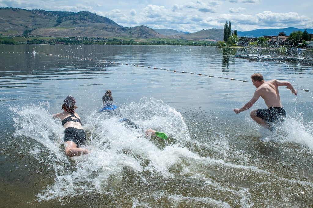 Students Shelby Schroeter, and Christine Gehringer and teacher Peter Gajda plunge into the water to swim at the start of the Ironman version of Storm the Wall. (Richard McGuire photo)