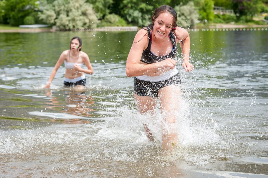 Christen Rausch runs ashore while Angel Thomas catches her breath after completing the swimming portion of the Storm the Wall relay. (Richard McGuire photo)
