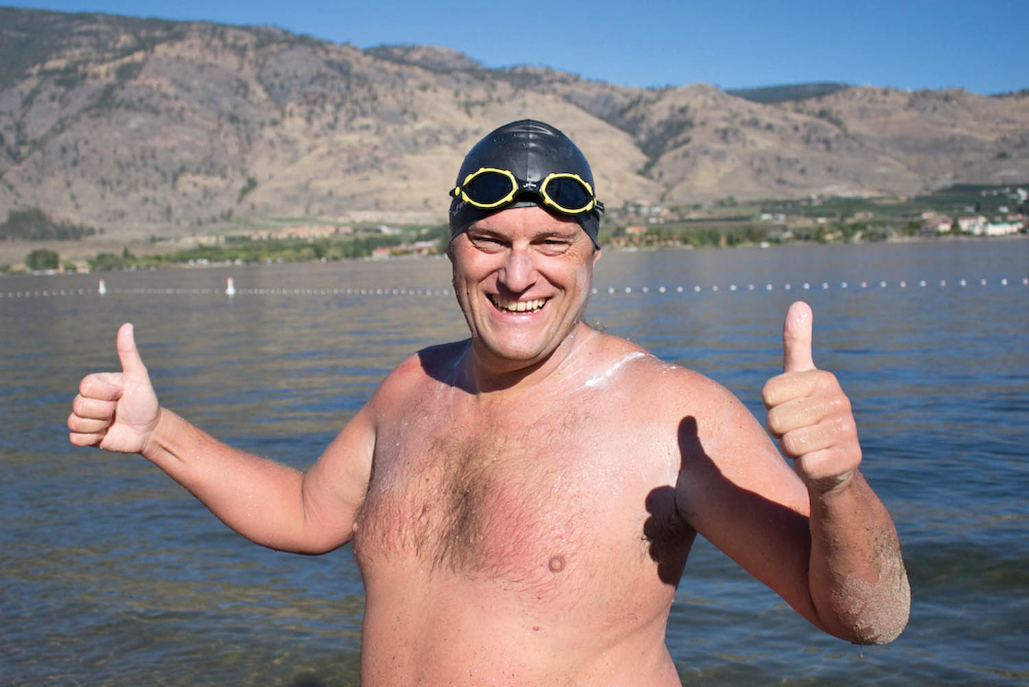Paul Duffield gives a thumbs up after arriving at Gyro Beach in Osoyoos five and three quarter hours after he left Veterans’ Memorial Park in Oroville. His challenges included navigating border formalities and swimming past Haynes Point Provincial Park when arthritis in his hands gave him pain. (Angelique Duffield photo)