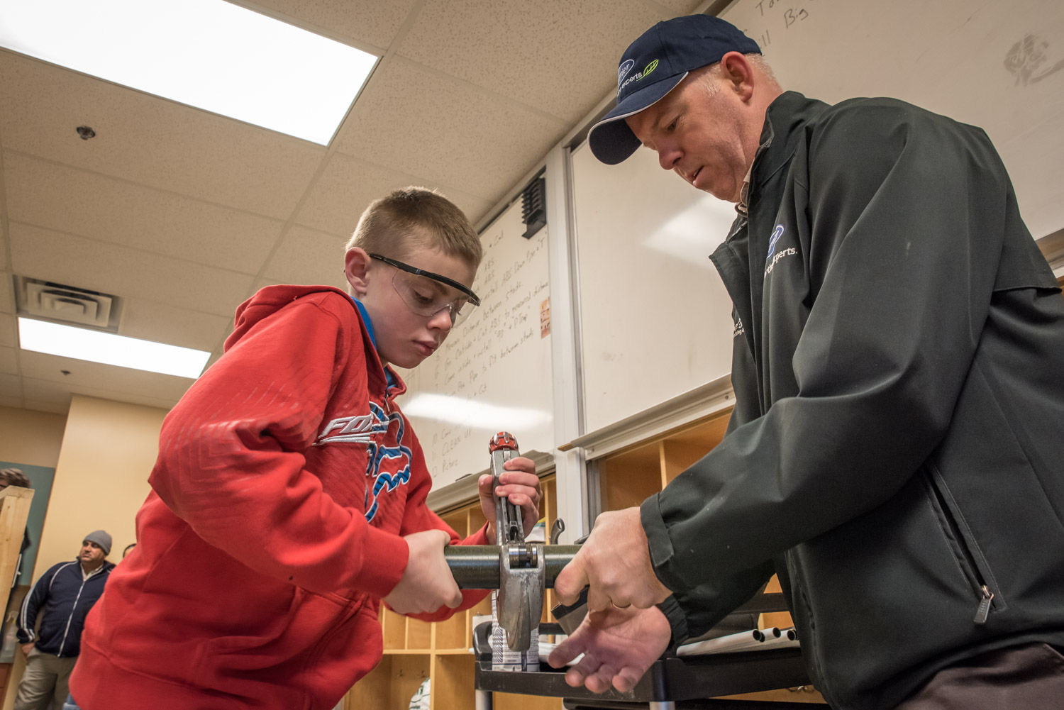 Noah Macor, a Grade 7 student at Osoyoos Elementary School, cuts a pipe with guidance from Brian Zakall of Joe's Plumbing. (Richard McGuire photo)