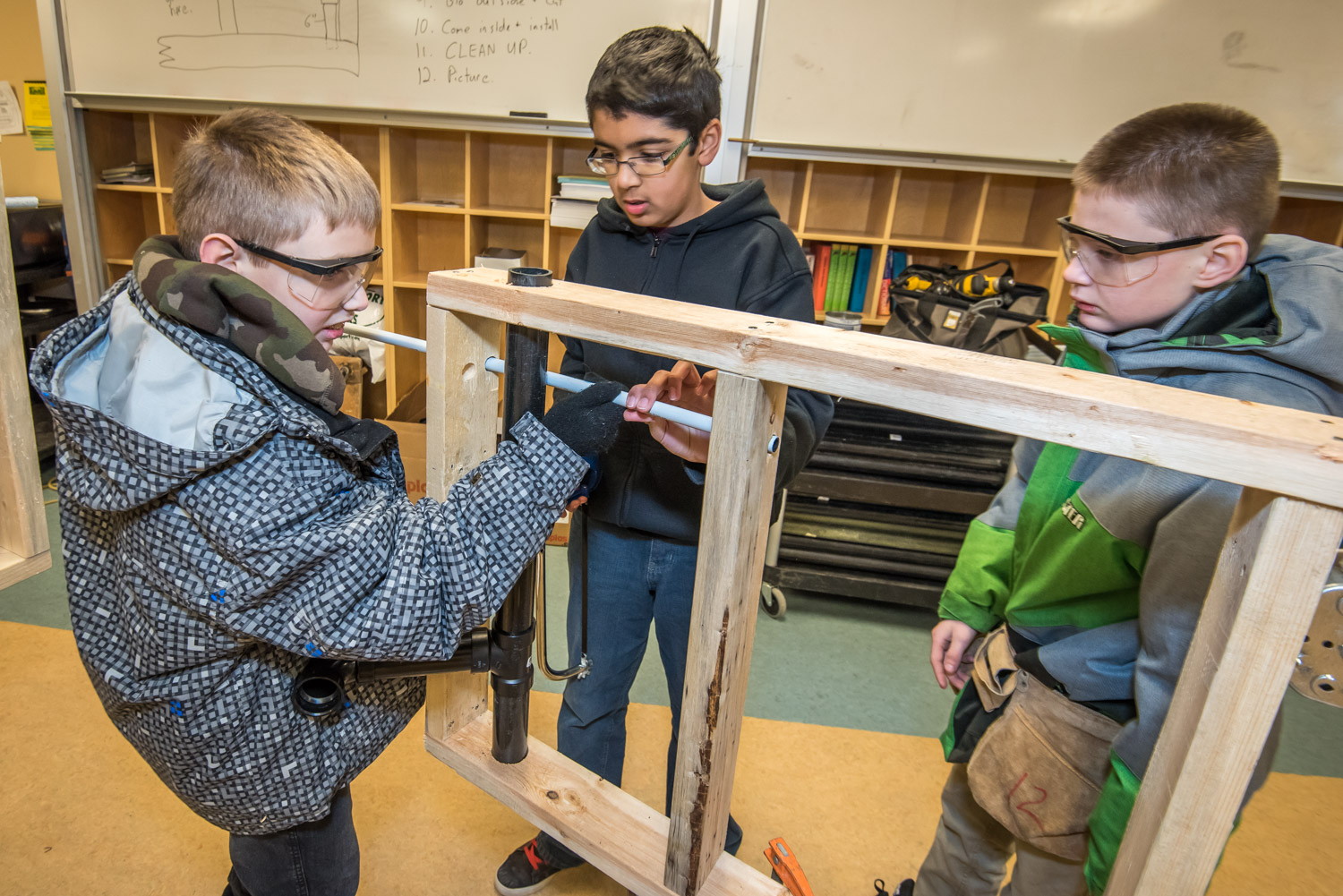 Jaston Peters (left) and Sukhman Kailay fit a pipe through a wooden frame while Lucas Deane looks on. The Grade 6 and 7 students were introduced to various building trades at Osoyoos Elementary School last week. (Richard McGuire photo)