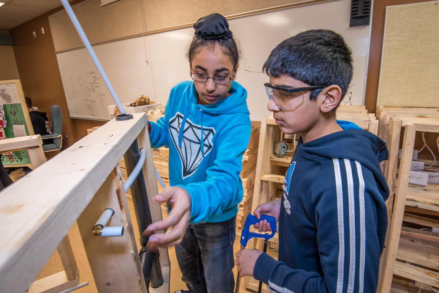 Jasmanpreet Sekhon (left) and Arshdeep Aulakh, Grade 7 students at Osoyoos Elementary School, fit a pipe through a wooden frame they've built. Last week students at the school were introduced to various building trades. (Richard McGuire photo)