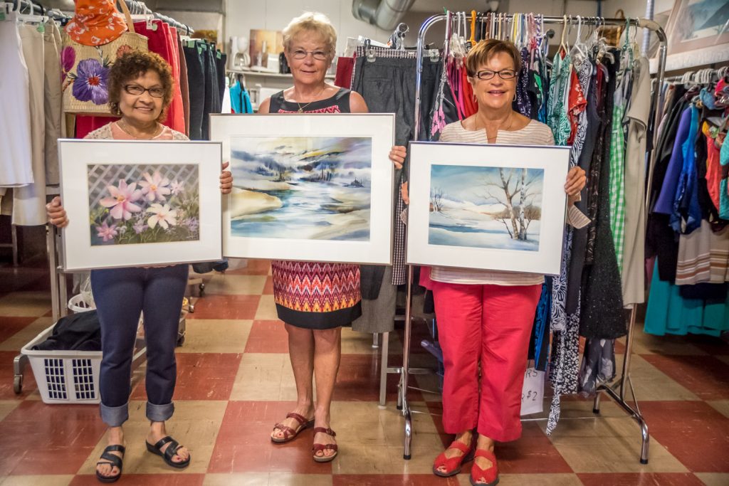 The Osoyoos United Church Thrift Shop normally sells used clothing and other items inexpensively, so this presented a dilemma to Manager Anne Polischuk when a donor contributed four beautiful watercolour paintings and suggested she should ask $200 each. Three were done by Penticton artist Marie Tolman in the 1990s and one, Polischuk's favourite, was done by Han Hunter. As of Monday, the paintings were still for sale and Polischuk is hoping to sell them to raise money for Fort McMurray fire victims. Last week the thrift shop raised nearly $2,000 in sales for Fort McMurray. Pictured here, Polischuk (centre), holds the Hunter painting, while thrift shop volunteers Lynette Gates (left) and Kathy Bourget (right) hold two of the three works by Tolman. (Richard McGuire photo)