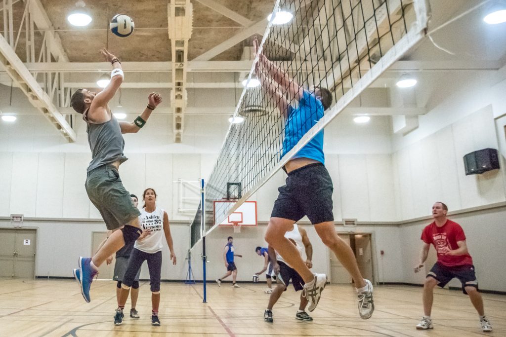 Tyler Fecyk, of Hogan's Heroes, leaps for a high ball (left) while Kenton Gilchirst of Desert Hills prepares to hit it back. In the background teammates Ashley Lotke-Schipholt and Ryan Dunkley keep an eye on the ball. (Richard McGuire photo)