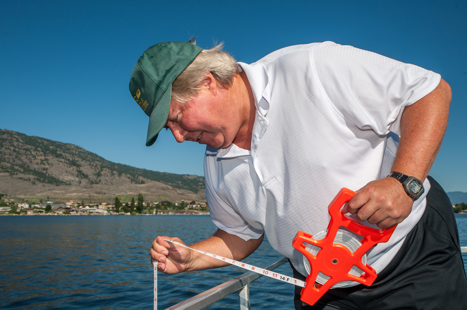 Brian Faltinson lowers a Secchi disk, used to measure the turbidity or clarity of water. A notable increase in turbidity can indicate a problem contaminating the water, in which case authorities are notified. (Richard McGuire photo)
