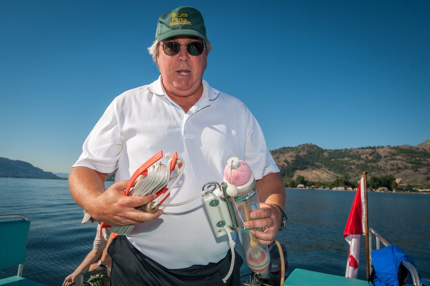 Brian Faltinson holds some of the equipment used to take measurements. On the left is a cord for a Secchi disk used to measure water clarity or turbidity and on the right is a container used to collect water at a depth to measure its pH level or acidity. (Richard McGuire photo)