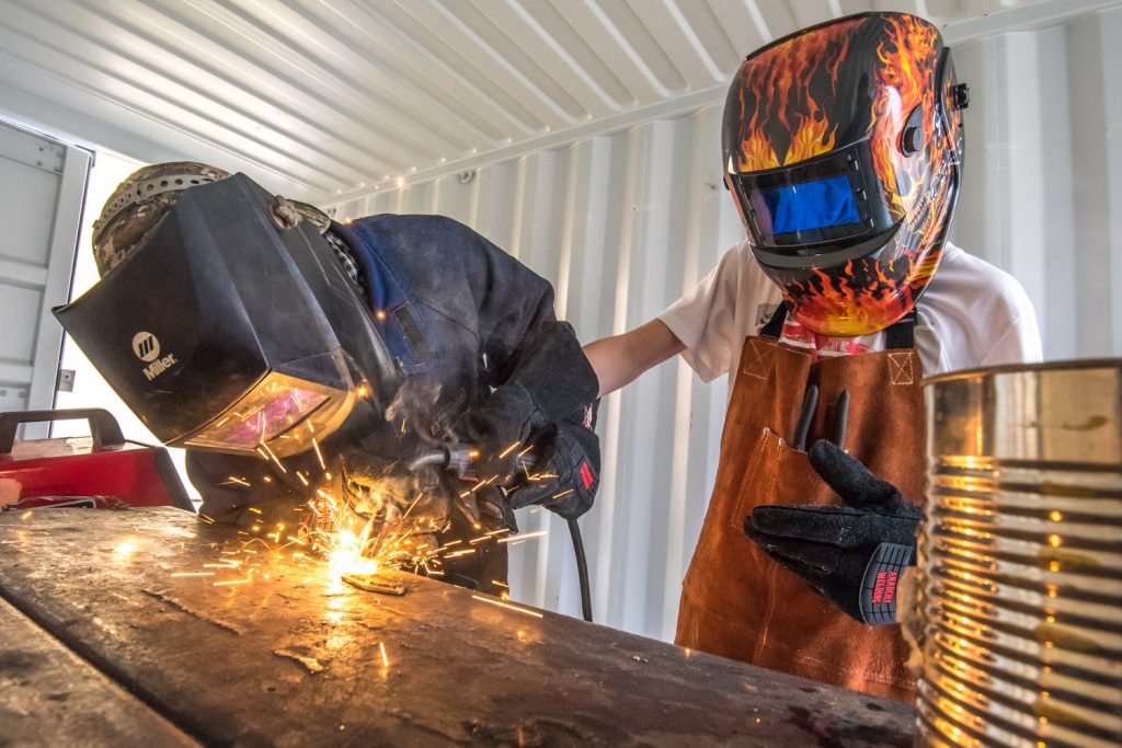 Ivan Gibbs (left), a local welder, was at Osoyoos Elementary School last Thursday giving students in grades 6 and 7 an introduction to welding. Pictured here, he helps Nathan Kaminski, a Grade 7 student, hold the torch as they weld initials on a piece of metal. Different activities took place each day last week at the school for Trades Week and this year's theme was metal fabrication and welding. Students also learned about safety and working with sheet metal. (Richard McGuire photo)