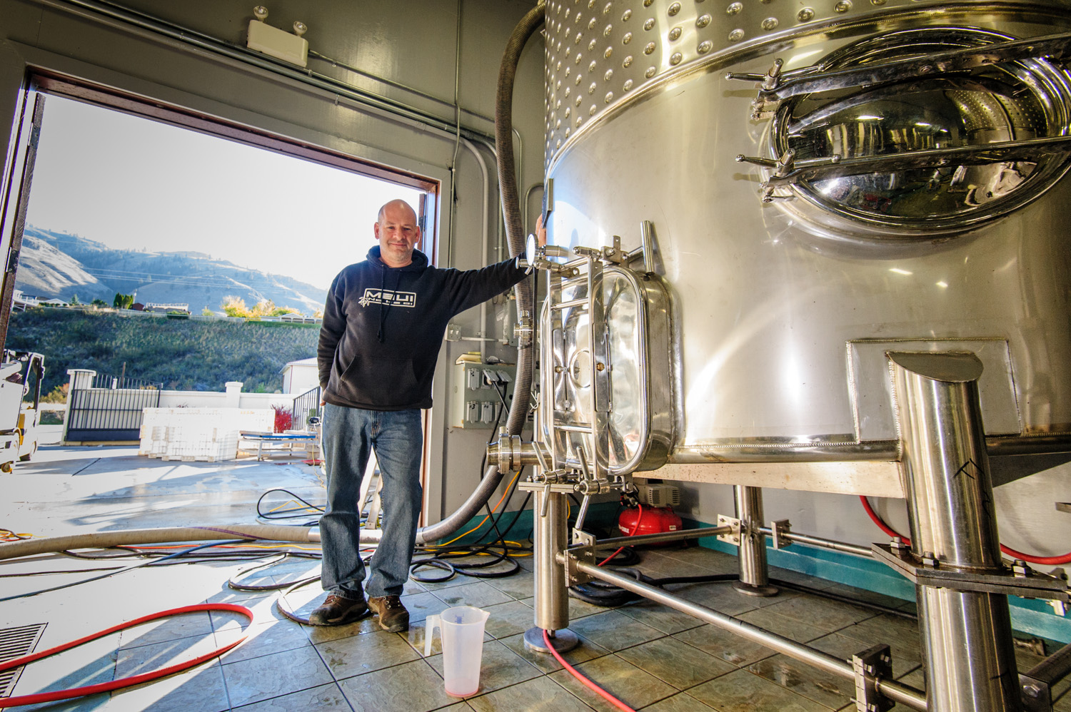 Winemaker Chris Tolley at Moon Curser Vineyards shows the giant tanks where juice from the grapes is collected prior to making wine in this file photo taken during harvest last year. (Richard McGuire photo)