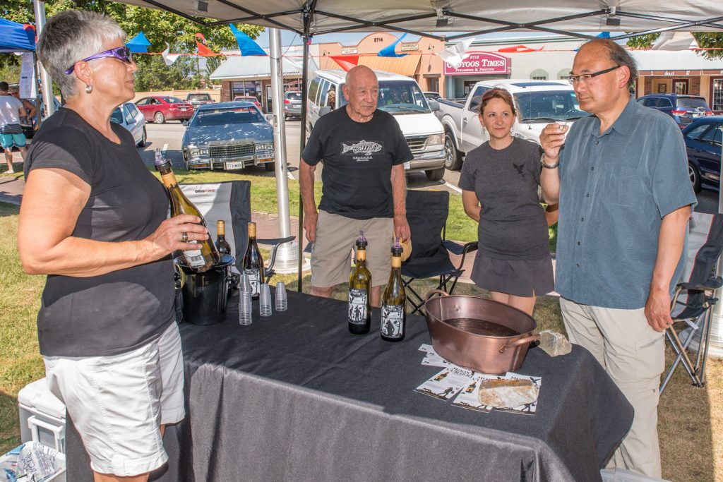 John Yap (right), the parliamentary secretary to B.C. Justice Minister Suzanne Anton, samples wine at the Moon Curser Vineyards booth at Market on Main last Saturday. From left are Beverly Forbes, Monty Tolley and Marisa Munday. Yap has been responsible for reforming B.C.'s liquor laws, including the change that allows local producers of beer, wine and spirits to sell and sample their products at farmers' markets. He toured Market on Main in Osoyoos on Saturday to find out how the program is working for local winemakers. (Richard McGuire photo)