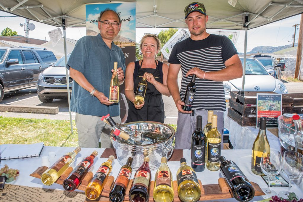 John Yap (left), the parliamentary secretary to B.C. Justice Minister Suzanne Anton, poses with Kim Brind'Amour, owner of Forbidden Fruit Winery, and her son Nathan Venables. Yap has been responsible for reforming B.C.'s liquor laws, including the change that allows local producers of beer, wine and spirits to sell and sample their products at farmers' markets. He toured Market on Main in Osoyoos on Saturday to find out how the program is working for local winemakers. (Richard McGuire photo)
